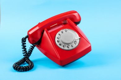 Photo of Red telephone with handset on light blue background