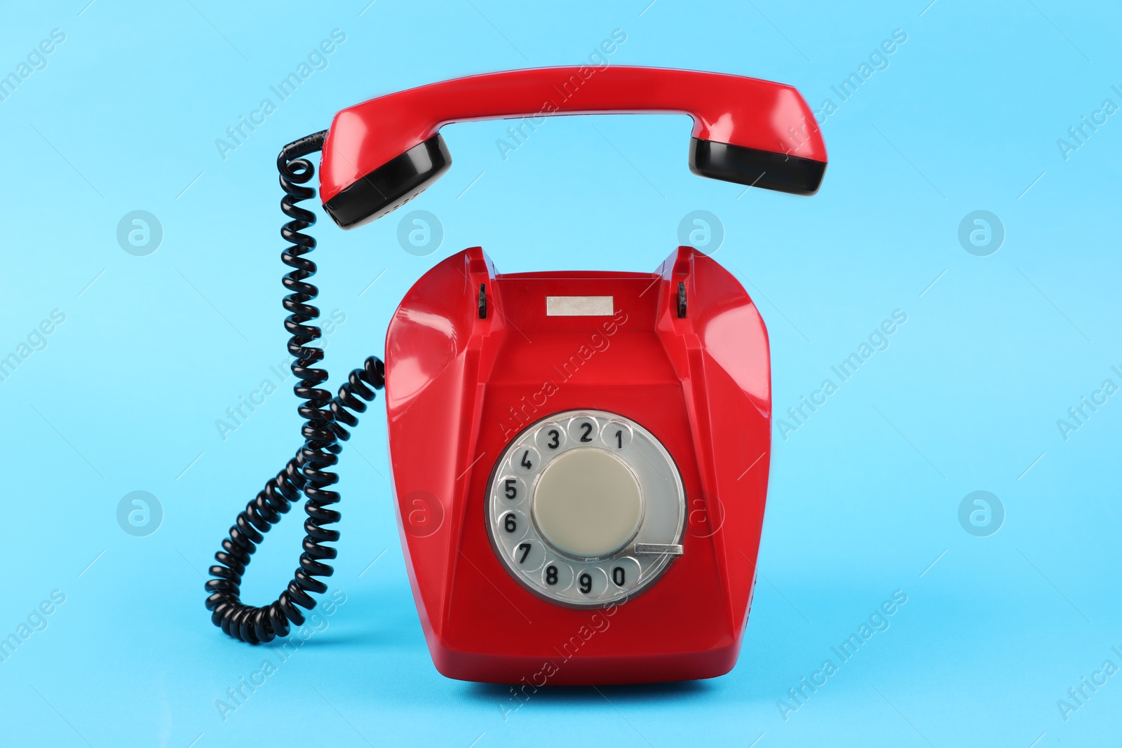 Photo of Red telephone with handset on light blue background