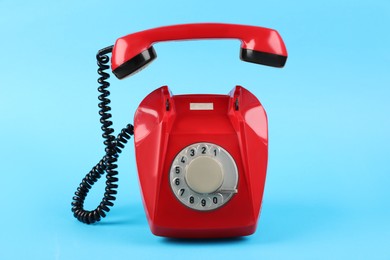 Photo of Red telephone with handset on light blue background