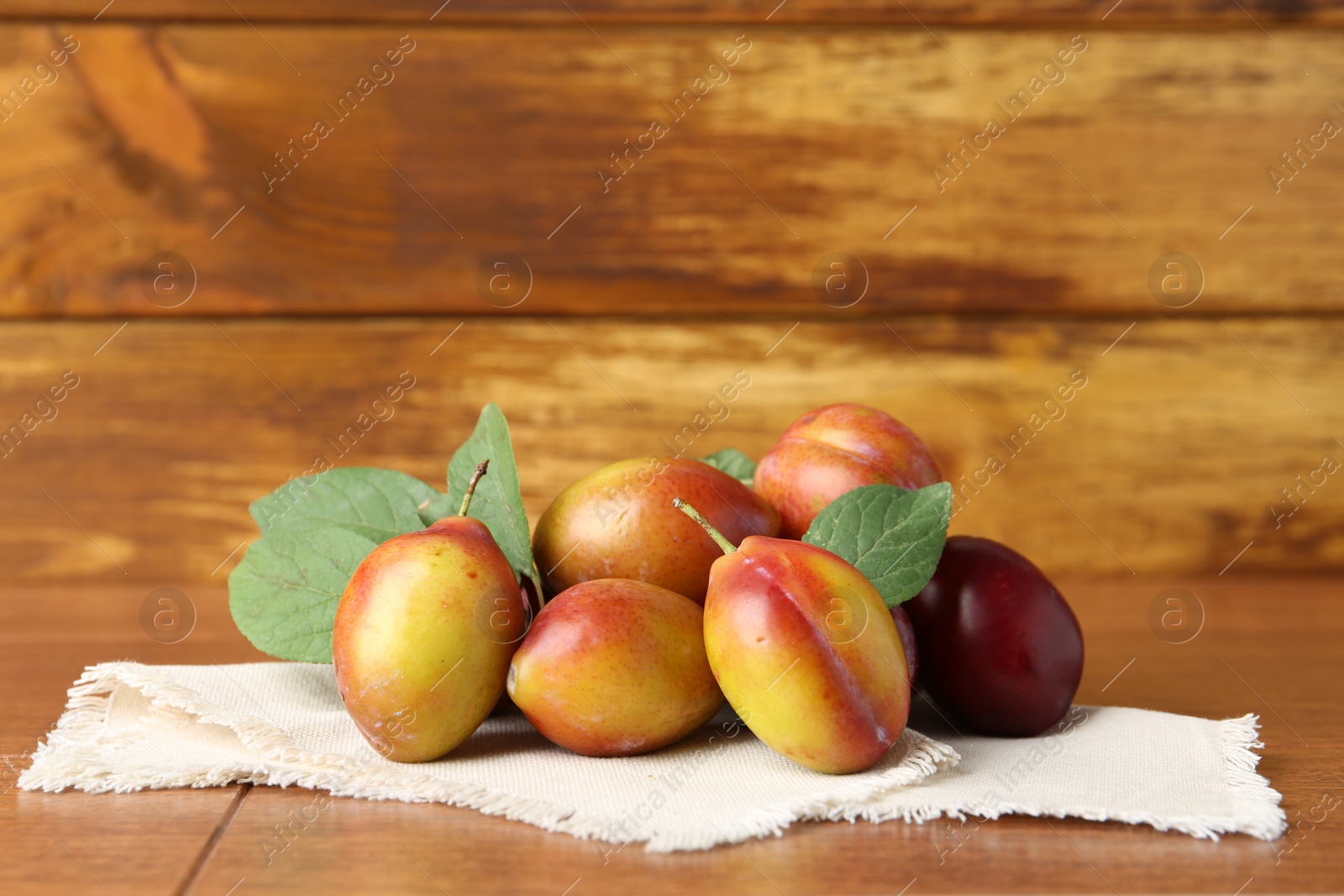 Photo of Ripe plums and leaves on wooden table