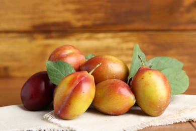 Photo of Ripe plums and leaves on table, closeup