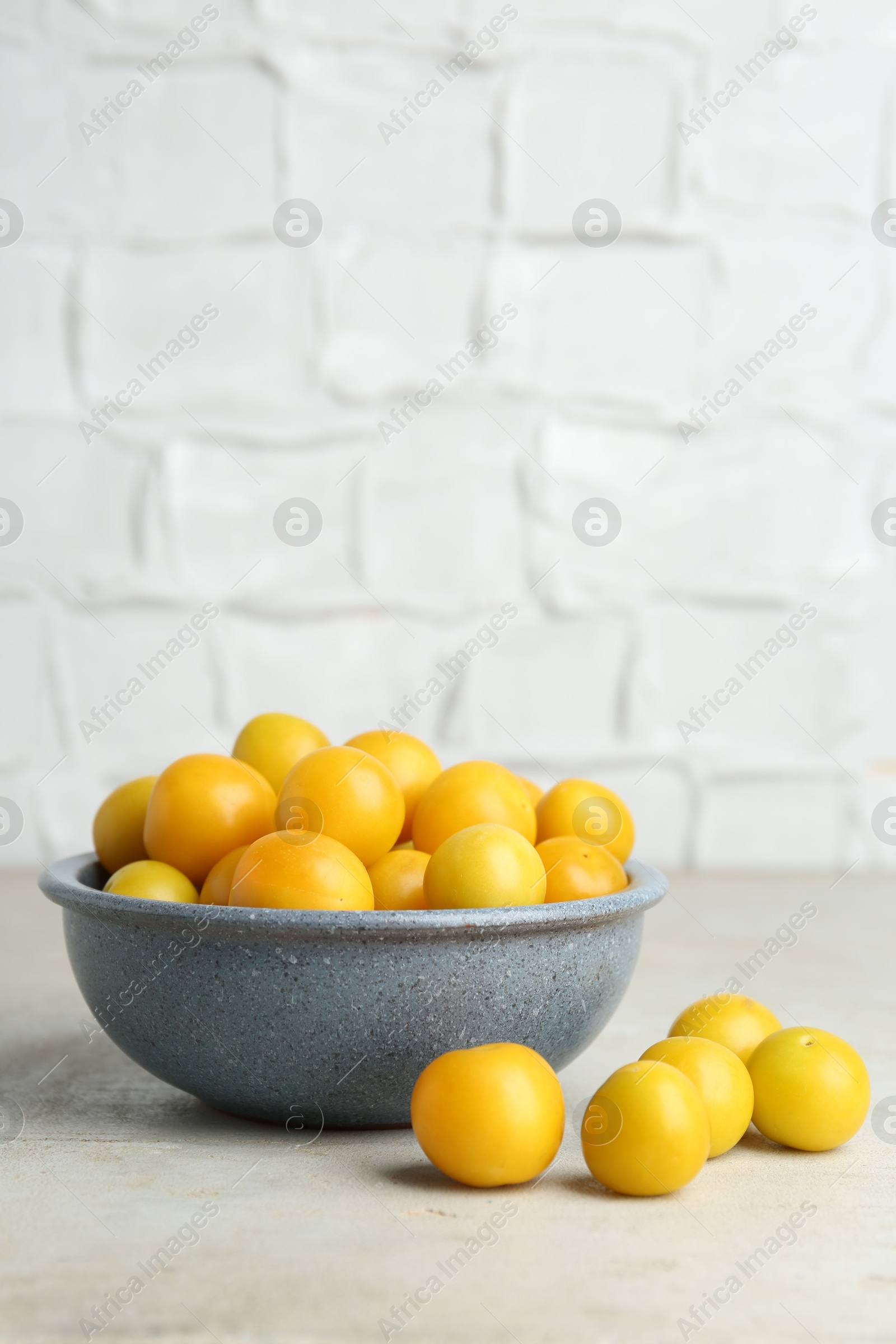 Photo of Ripe plums in bowl on light textured table