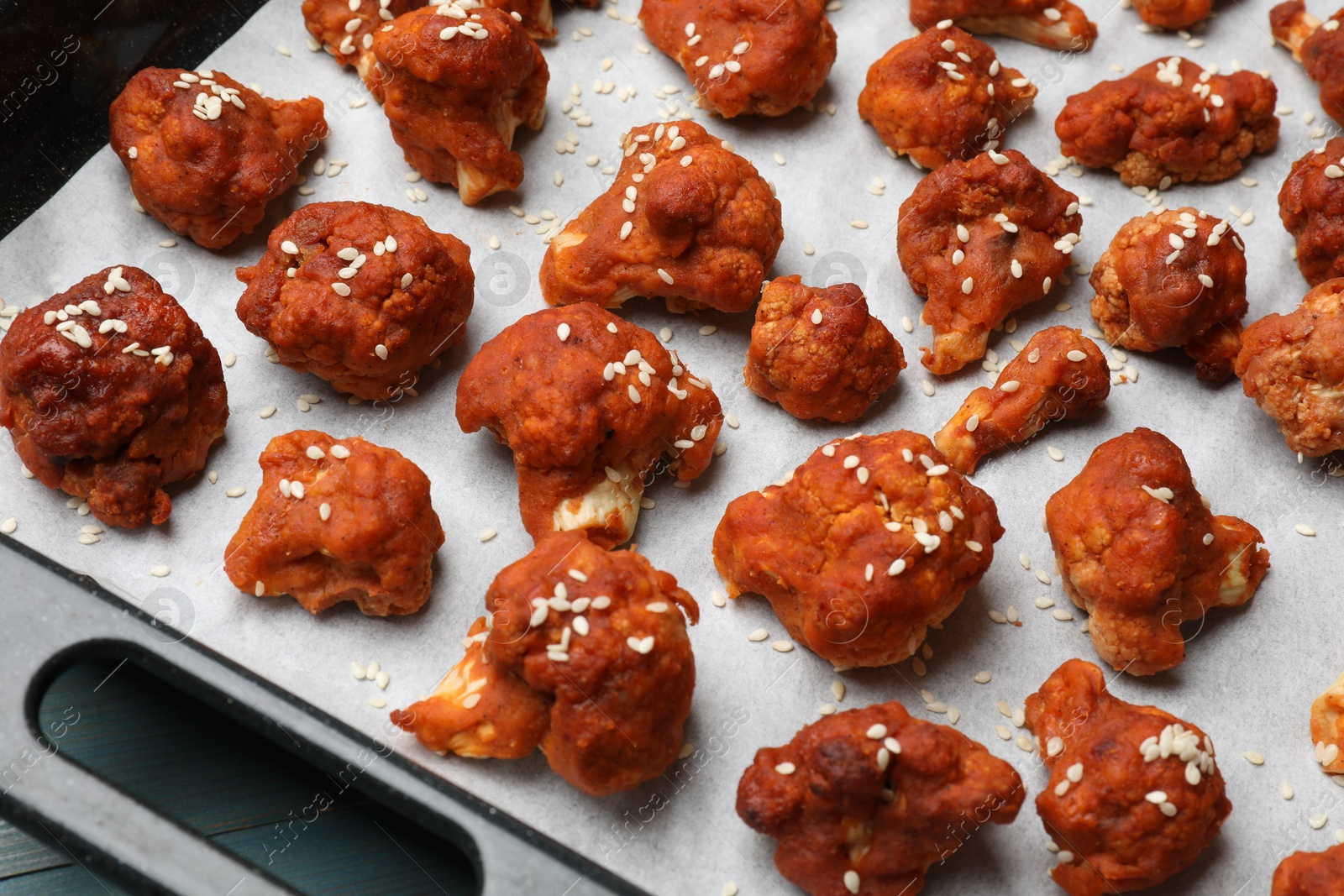 Photo of Tray with tasty cauliflower buffalo wings on light blue wooden table, closeup