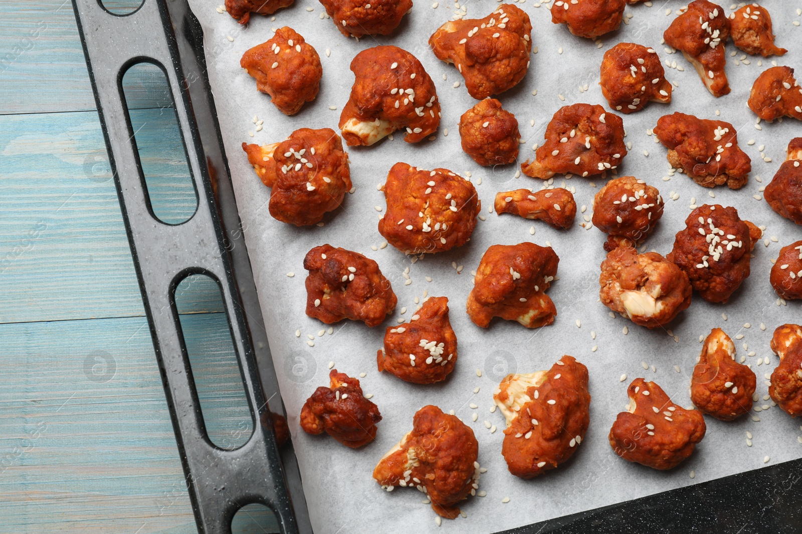 Photo of Tray with tasty cauliflower buffalo wings on light blue wooden table, top view