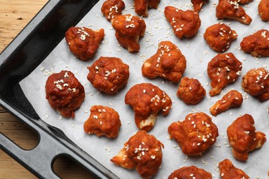 Photo of Tray with tasty cauliflower buffalo wings on wooden table, top view