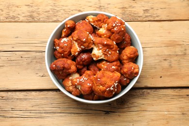 Photo of Tasty cauliflower buffalo wings in bowl on wooden table, top view