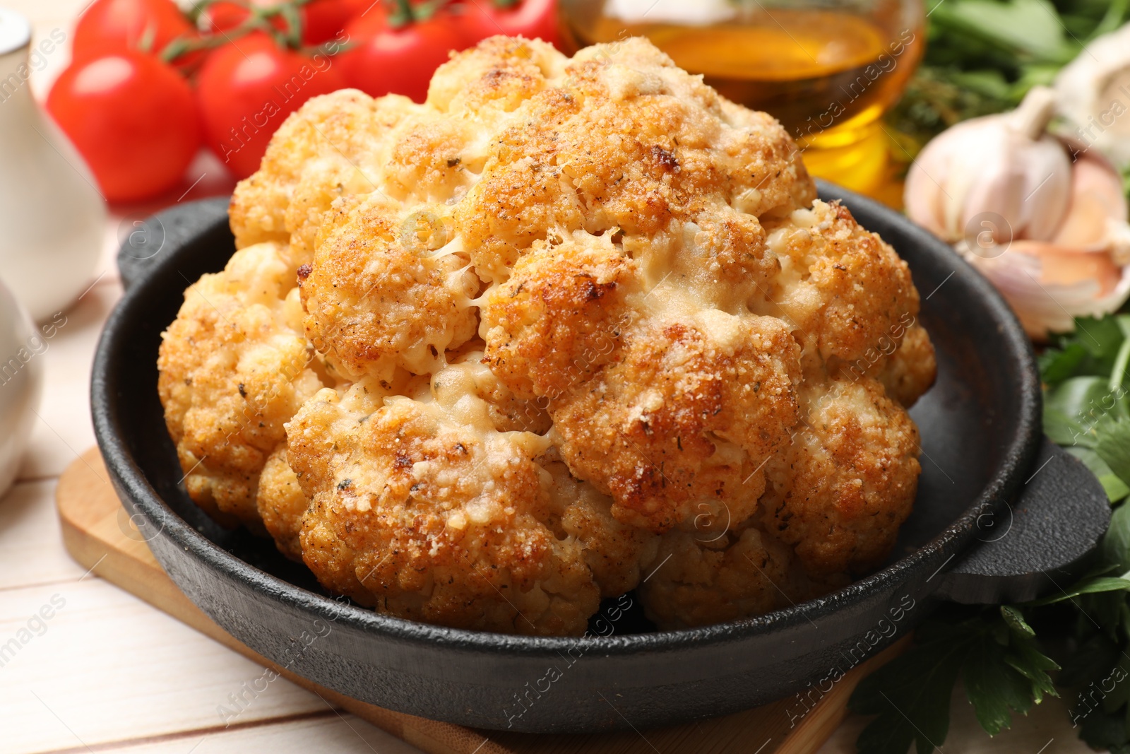 Photo of Delicious baked cauliflower and products on wooden table, closeup