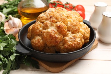 Photo of Delicious baked cauliflower and products on wooden table, closeup