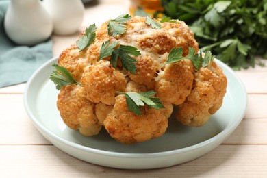 Delicious baked cauliflower with parsley on wooden table, closeup