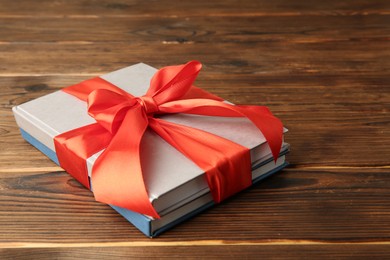 Photo of Books with ribbon as gift on wooden table