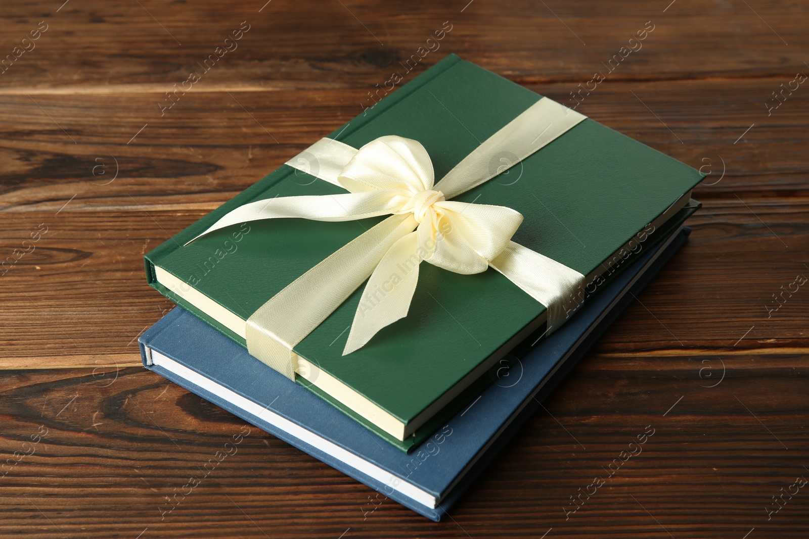 Photo of Books with ribbon as gift on wooden table