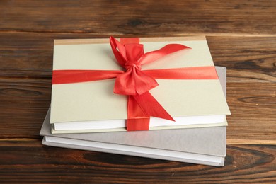 Photo of Books with ribbon as gift on wooden table