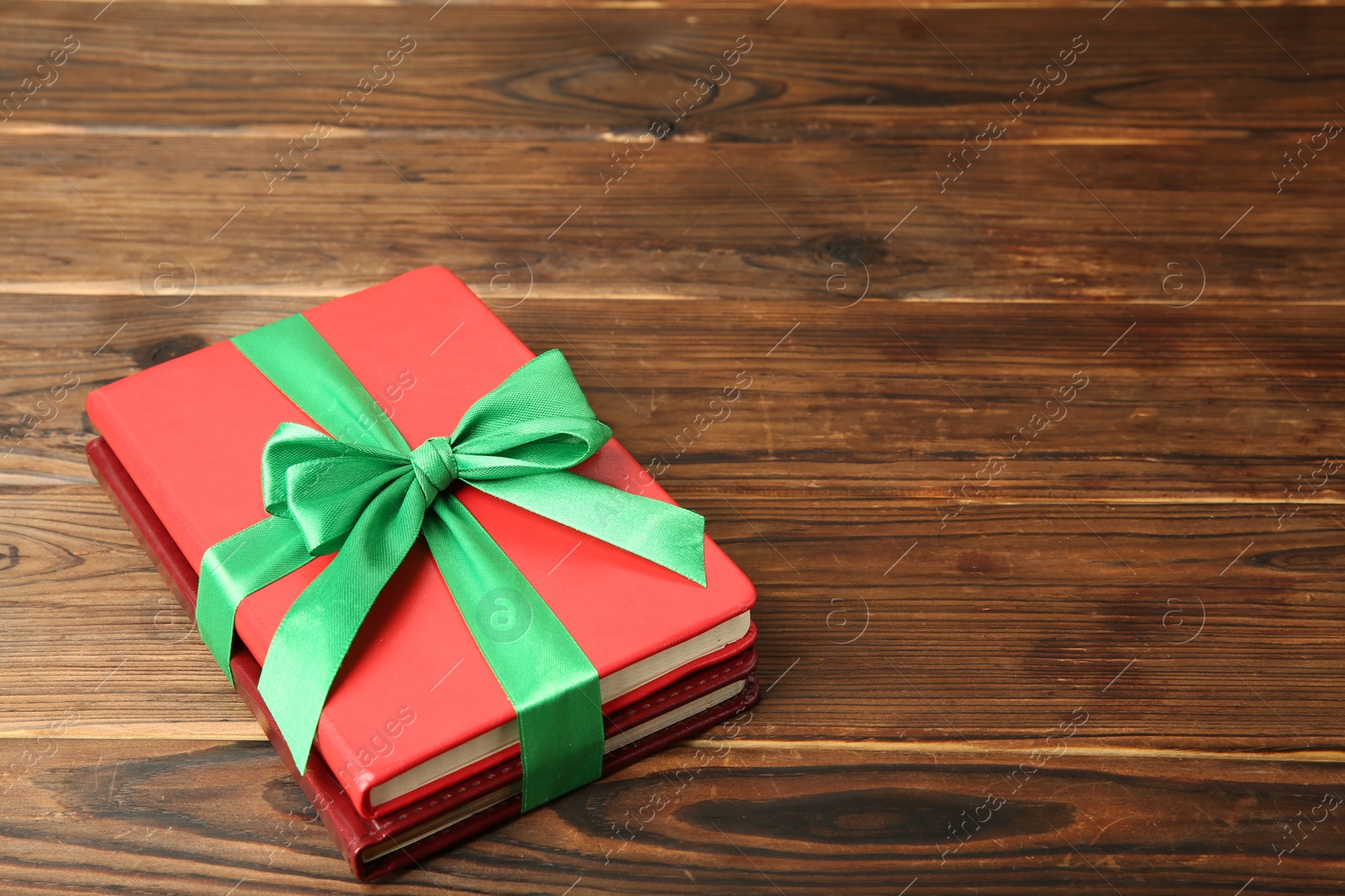 Photo of Books with ribbon as gift on wooden table, space for text