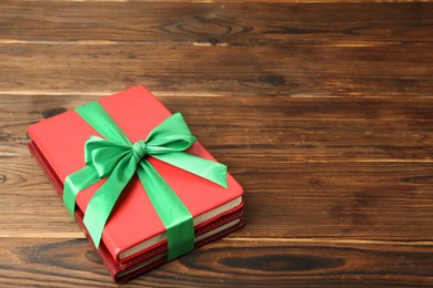 Photo of Books with ribbon as gift on wooden table, space for text