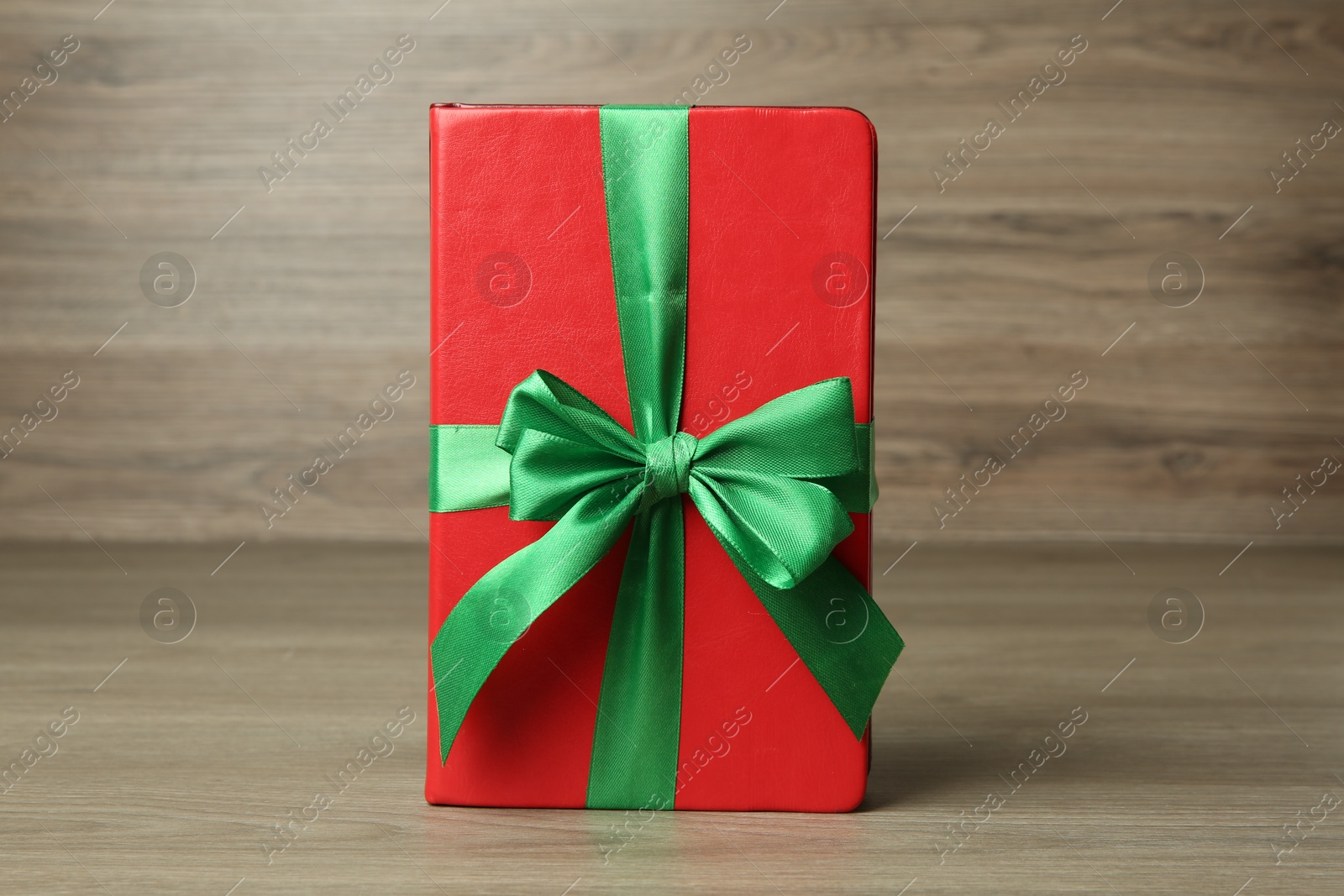 Photo of Book with ribbon as gift on wooden table