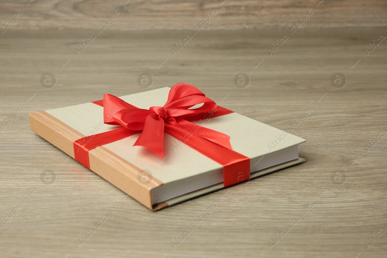 Photo of Book with ribbon as gift on wooden table