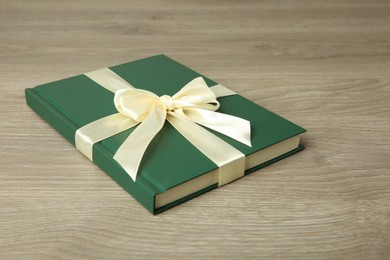 Photo of Book with ribbon as gift on wooden table