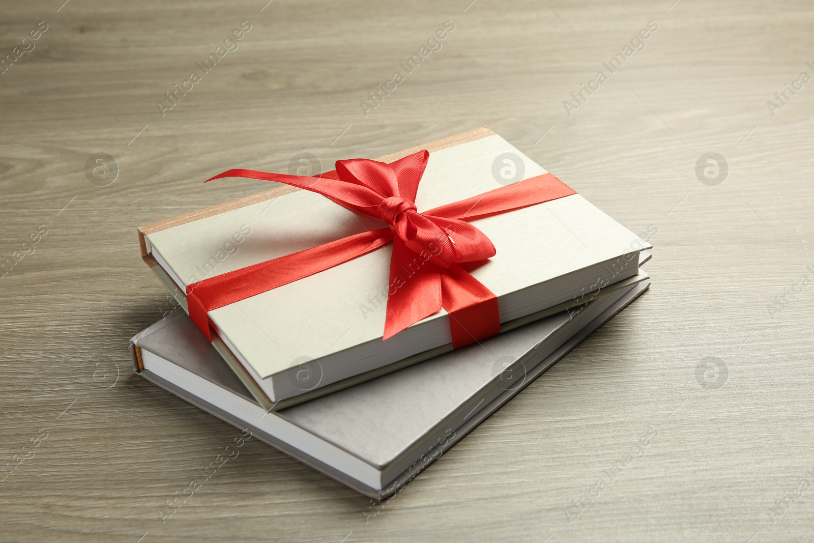 Photo of Books with ribbon as gift on wooden table