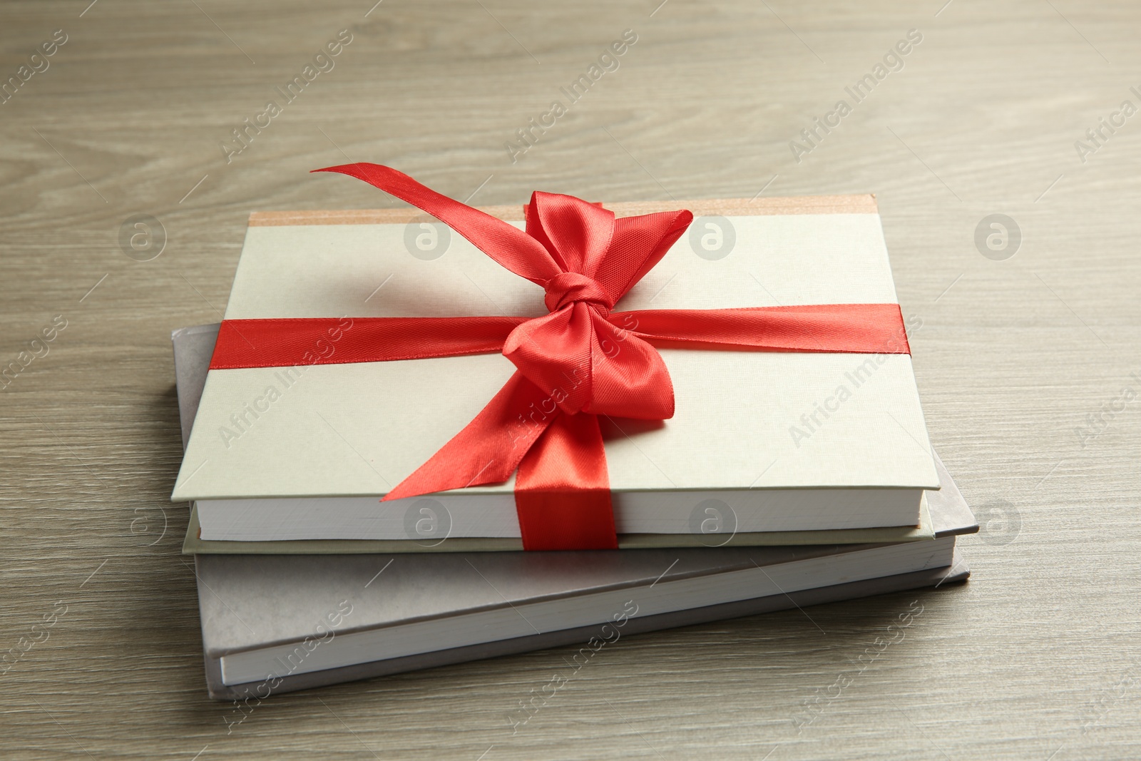 Photo of Books with ribbon as gift on wooden table