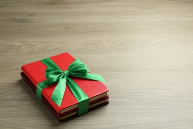 Photo of Books with ribbon as gift on wooden table, space for text