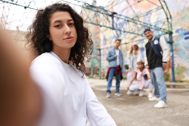 Image of Young woman taking selfie with group of people outdoors, selective focus. Hip hop dancers