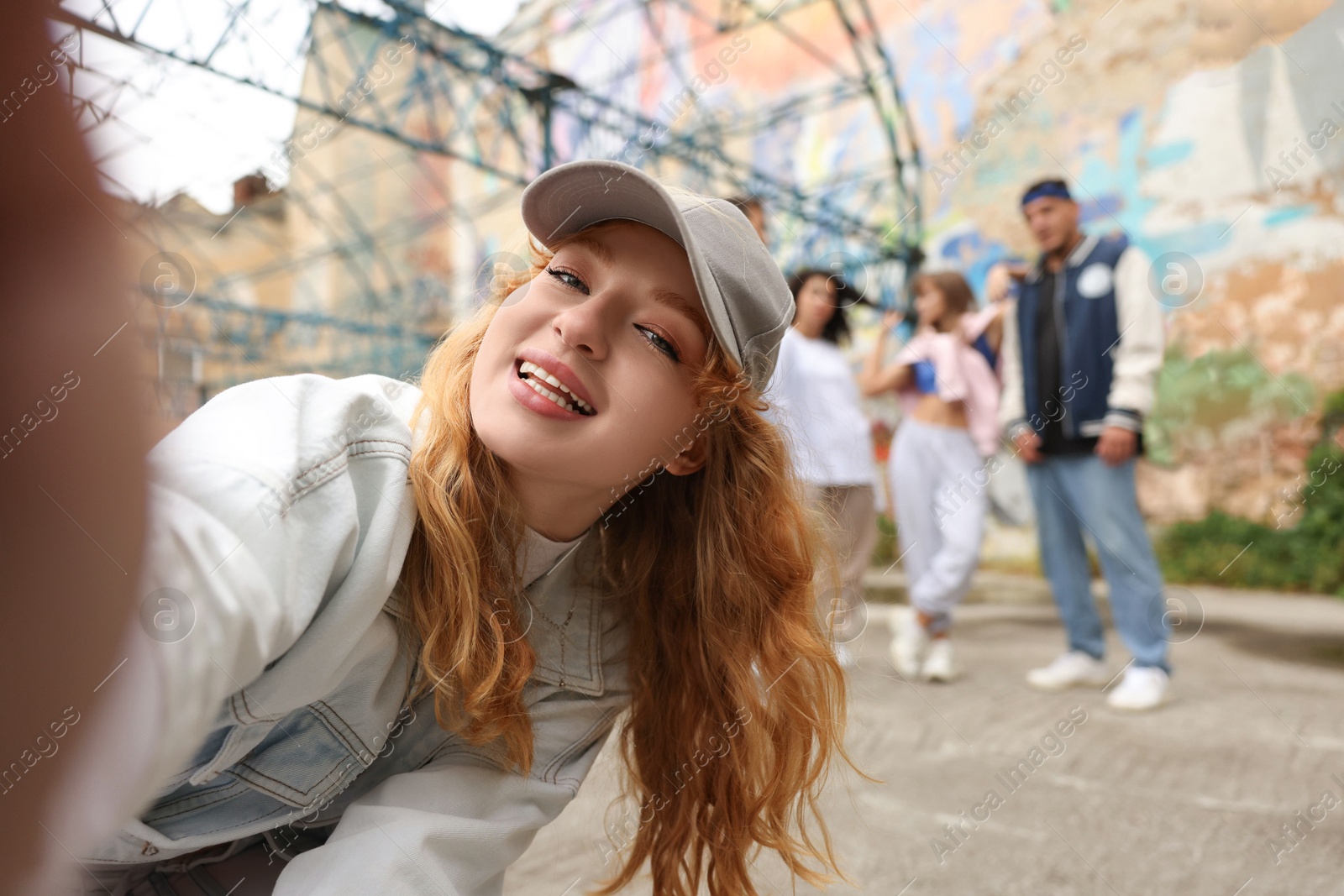 Image of Young woman taking selfie with group of people outdoors, selective focus. Hip hop dancers