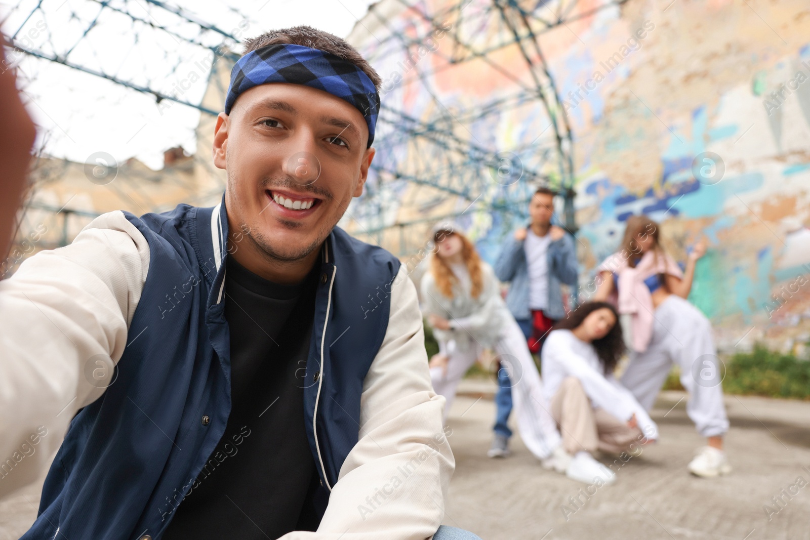 Image of Man taking selfie with group of people outdoors, selective focus. Hip hop dancers