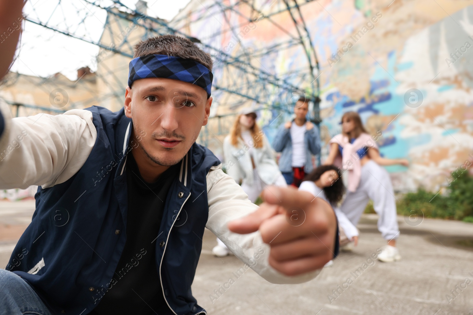 Image of Man taking selfie with group of people outdoors, selective focus. Hip hop dancers