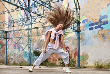 Beautiful young woman dancing hip hop outdoors