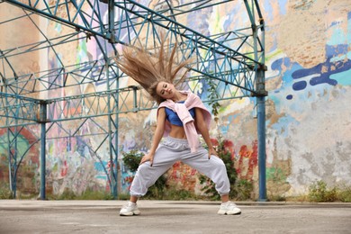 Image of Beautiful young woman dancing hip hop outdoors