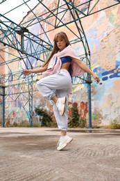 Image of Beautiful young woman dancing hip hop outdoors, low angle view