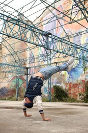 Image of Man doing handstand outdoors. Hip hop dancer