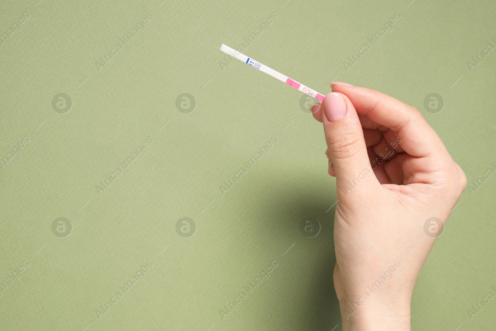 Photo of Woman holding pregnancy test on olive background, top view. Space for text