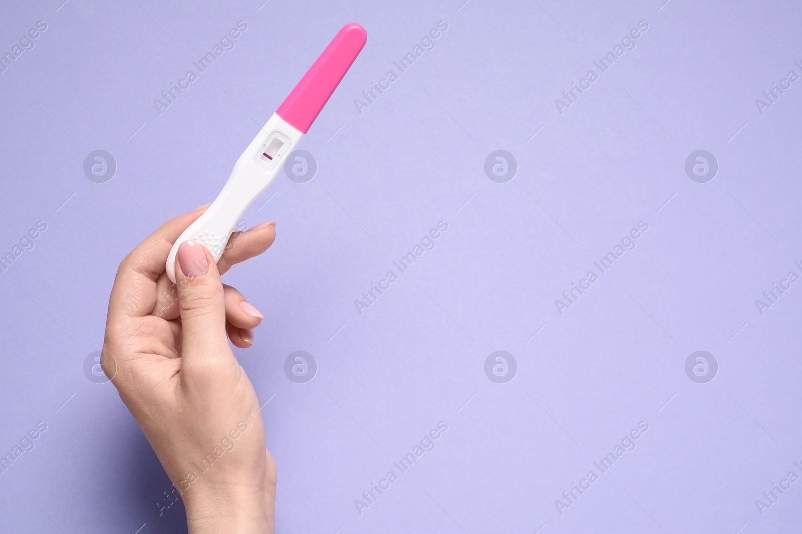 Photo of Woman holding pregnancy test on violet background, top view. Space for text