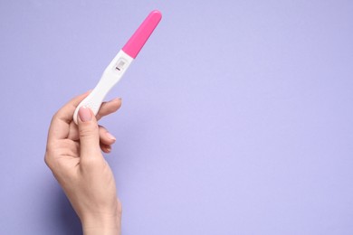 Woman holding pregnancy test on violet background, top view. Space for text