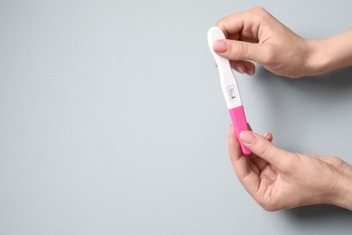 Photo of Woman with pregnancy test on light grey background, top view. Space for text