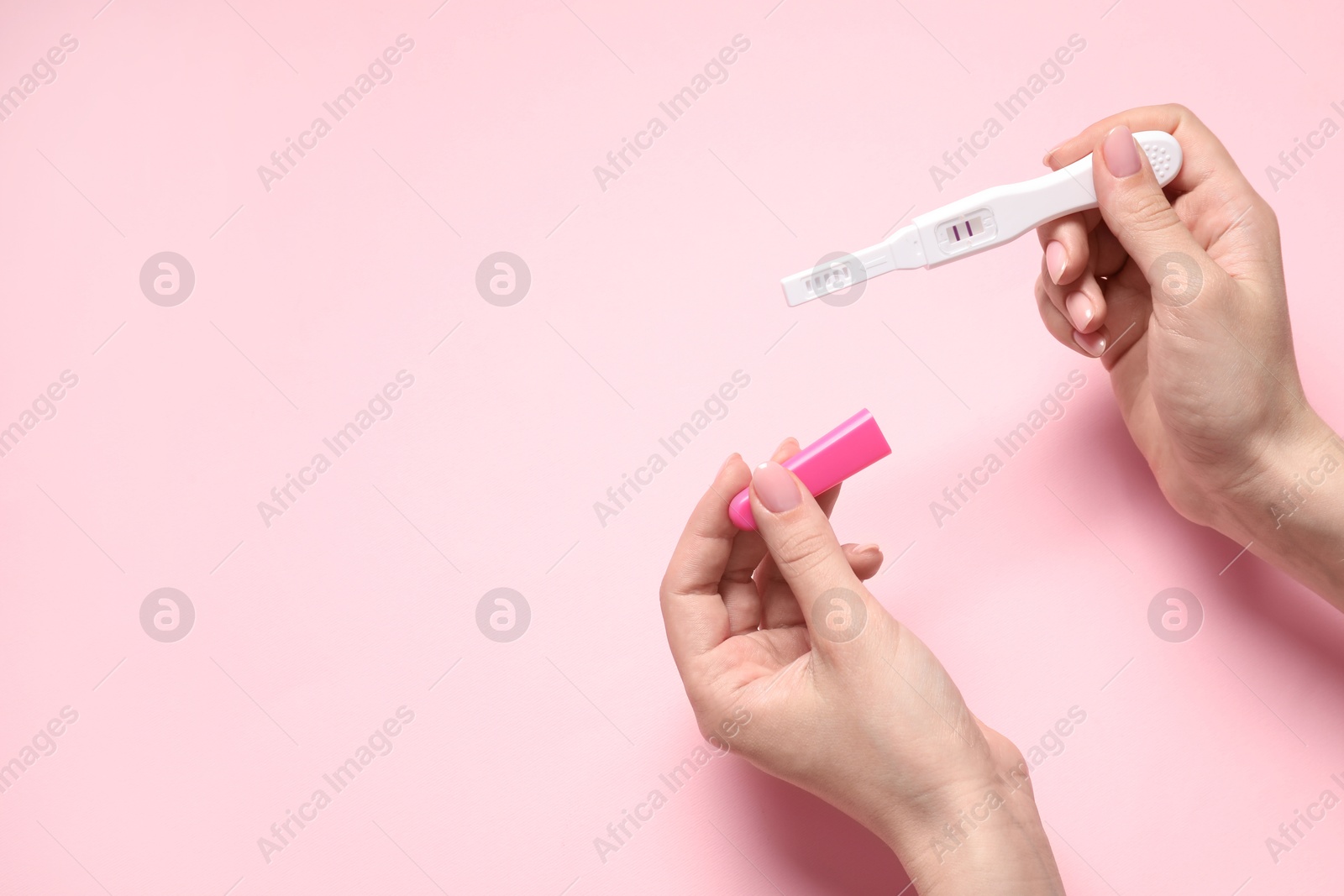 Photo of Woman holding pregnancy test on pink background, closeup. Space for text