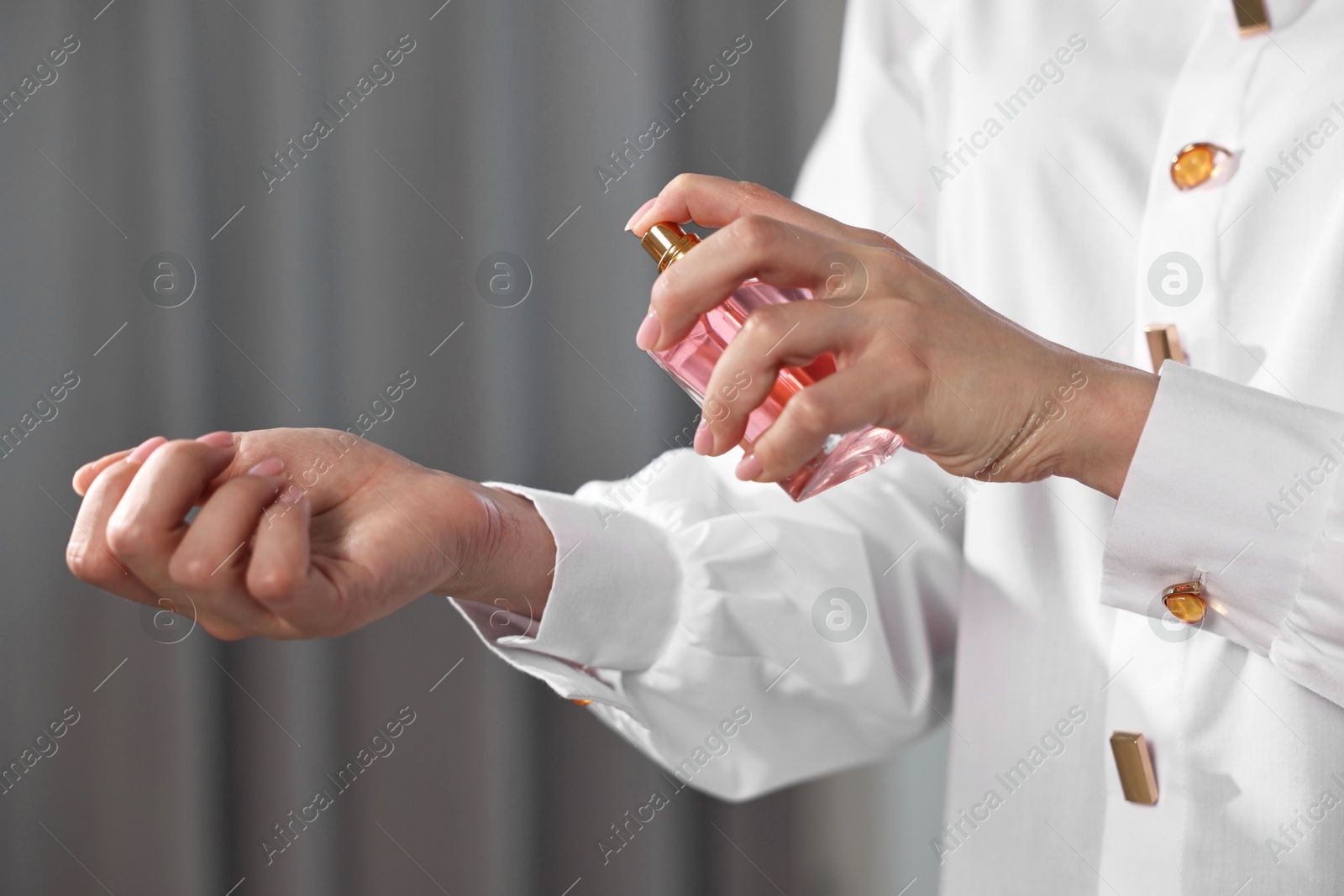 Photo of Woman spraying perfume onto wrist indoors, closeup