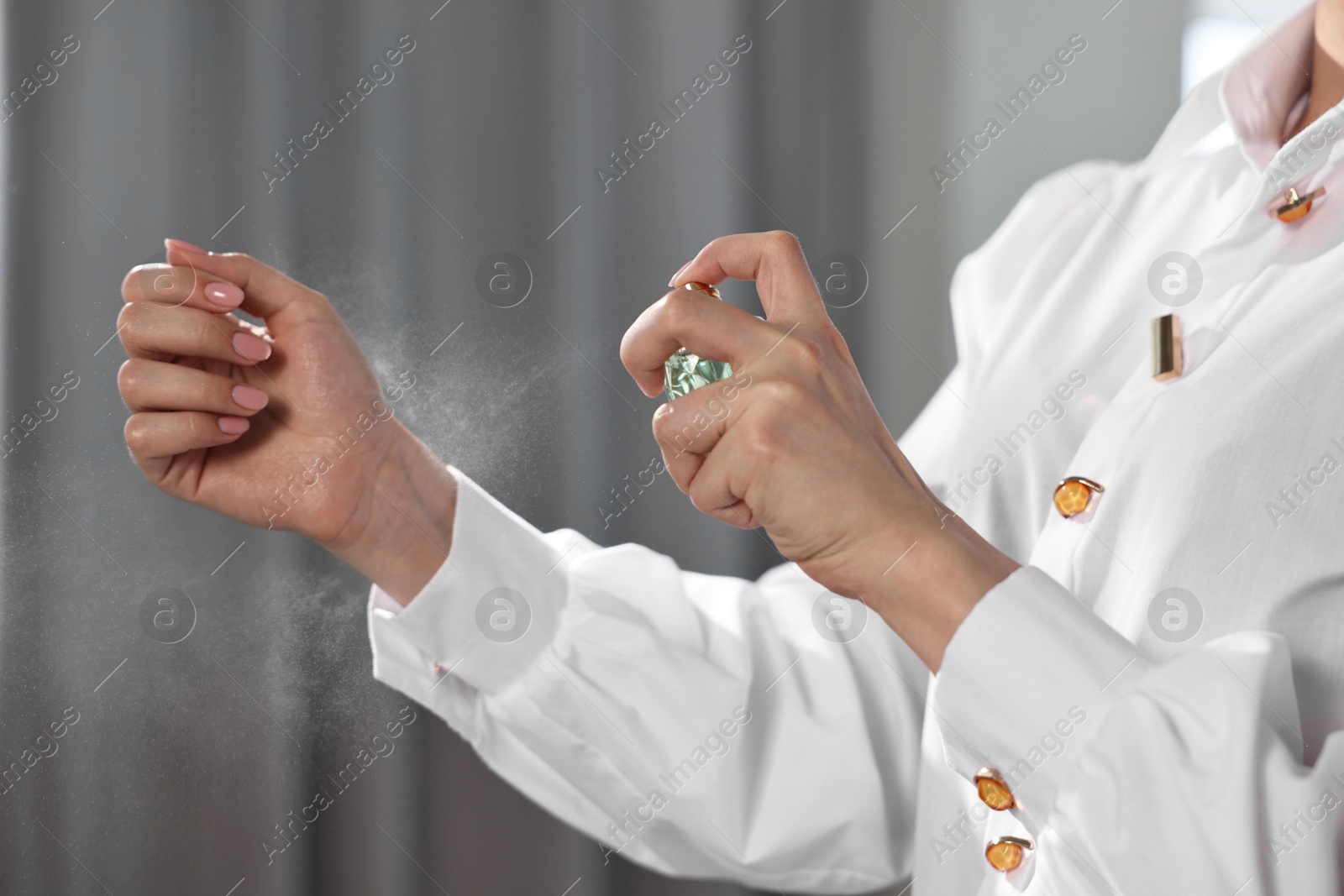 Photo of Woman spraying perfume onto wrist indoors, closeup