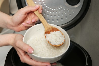 Photo of Woman taking boiled rice into bowl on grey background, closeup