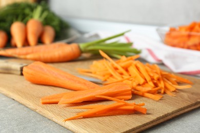 Photo of Pieces of fresh carrots on gray textured table, closeup