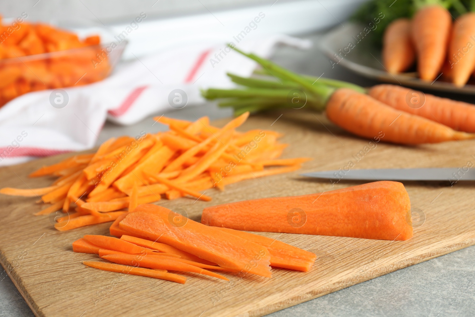 Photo of Pieces of fresh carrots on gray table, closeup