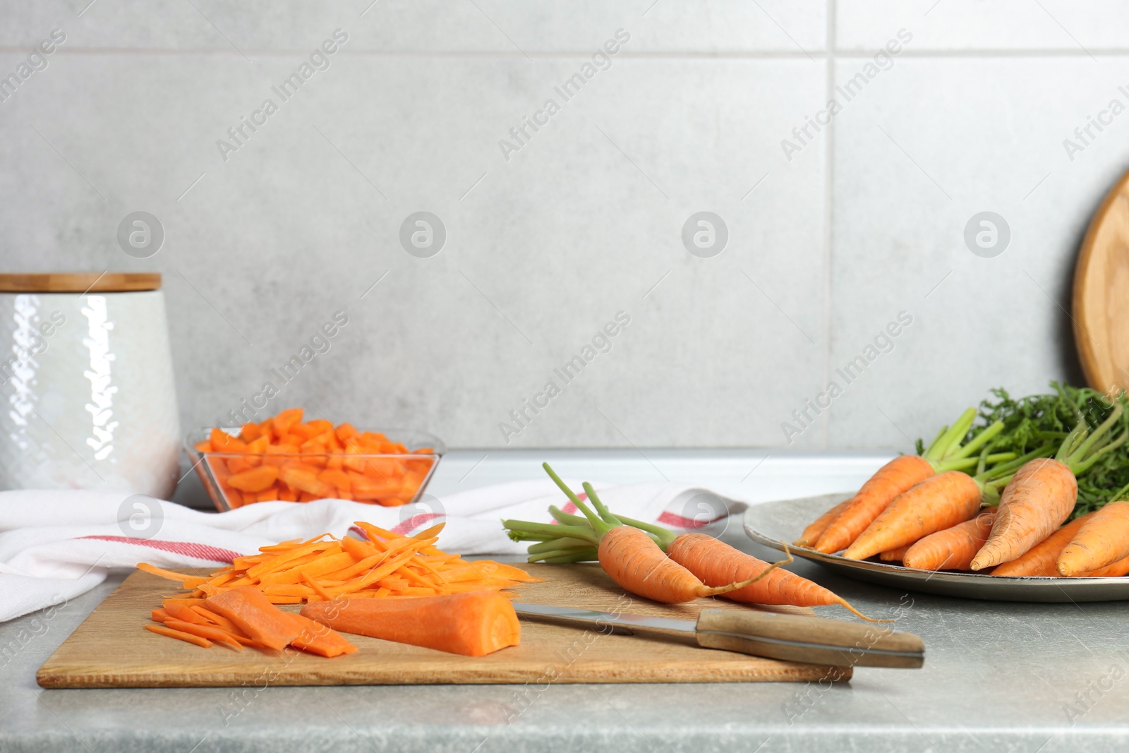 Photo of Fresh carrots and knife on gray textured table in kitchen