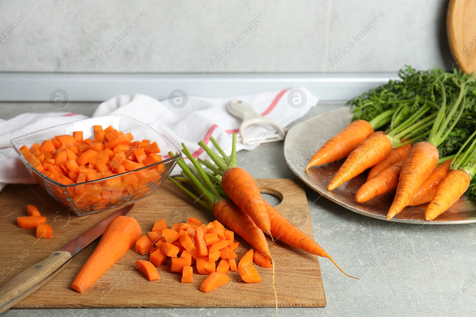 Photo of Fresh carrots and knife on gray textured table in kitchen