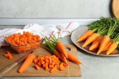 Photo of Fresh carrots and knife on gray textured table in kitchen