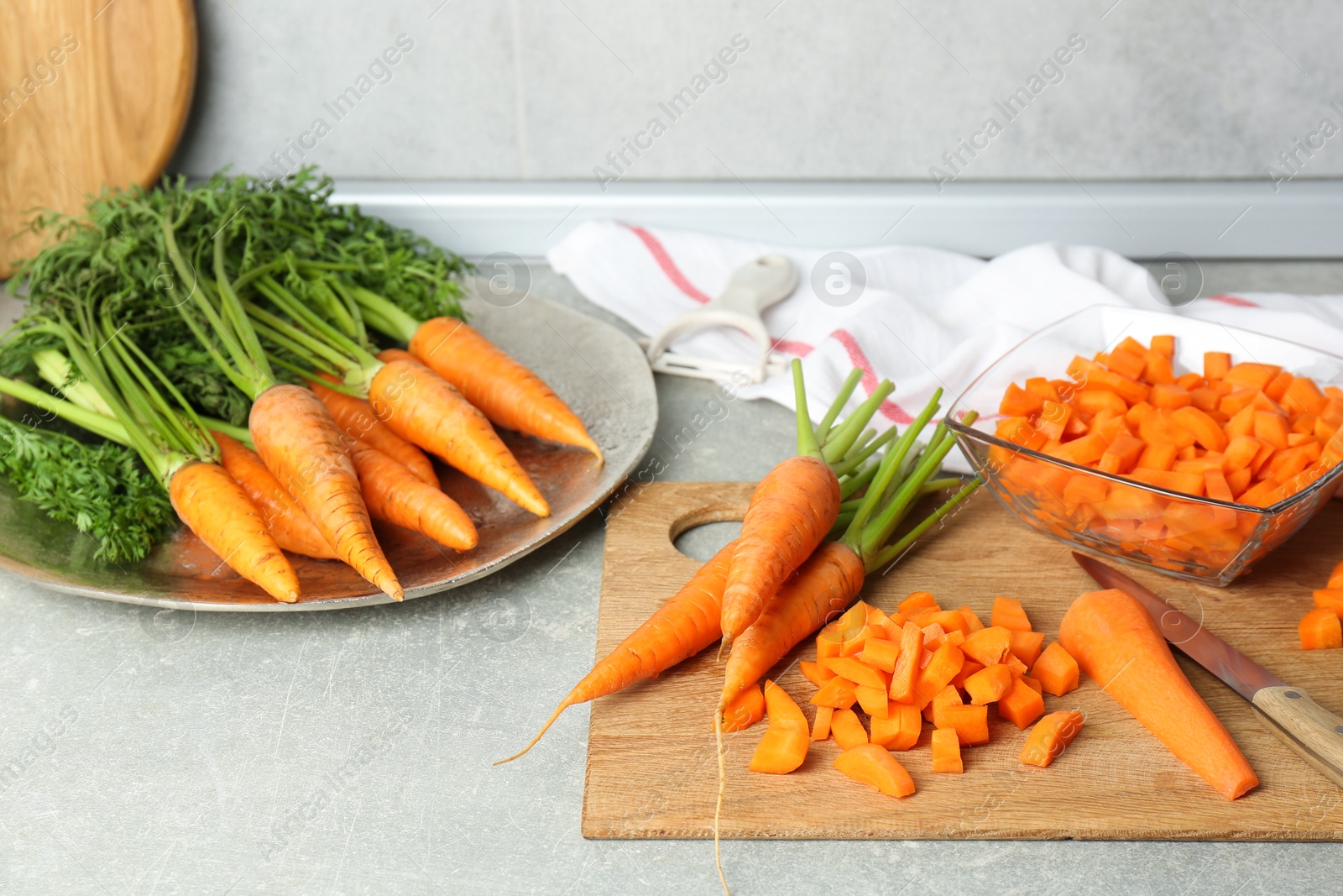 Photo of Fresh carrots and knife on gray textured table in kitchen