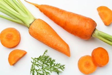 Photo of Whole and cut fresh carrots on white background, top view