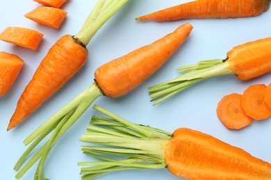 Photo of Whole and cut fresh carrots on light background, flat lay