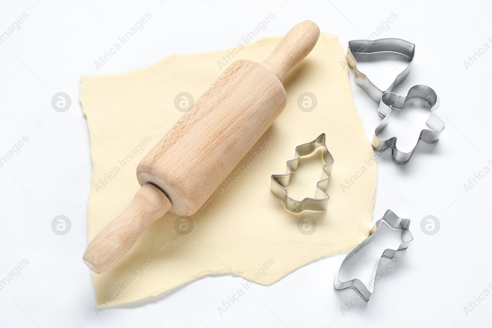 Photo of Raw dough, rolling pin and cookie cutters on white background