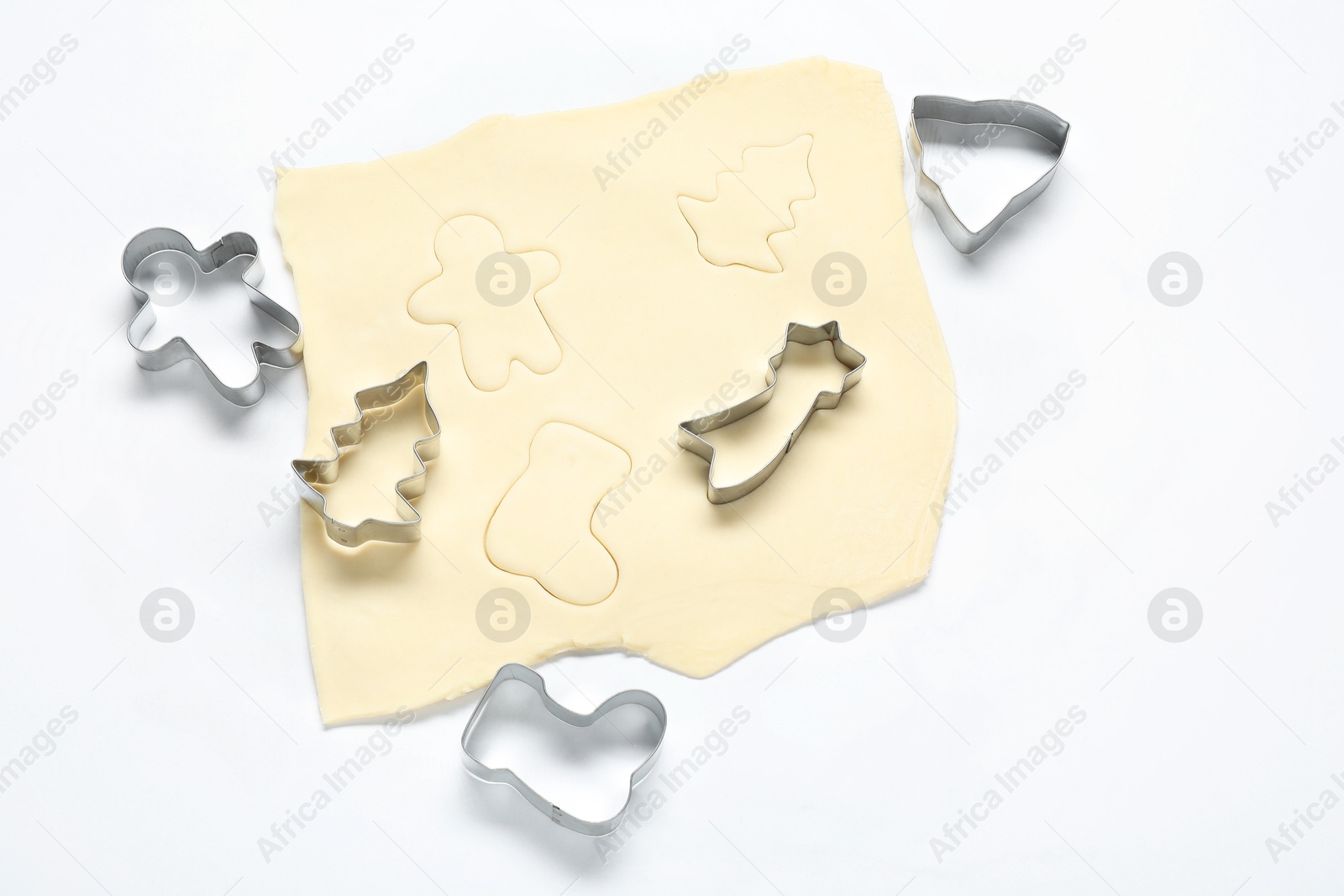 Photo of Raw dough and cookie cutters on white background, above view